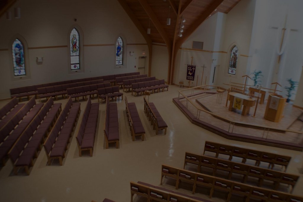 Interior of a church sanctuary with pews, altar, and stained-glass windows.