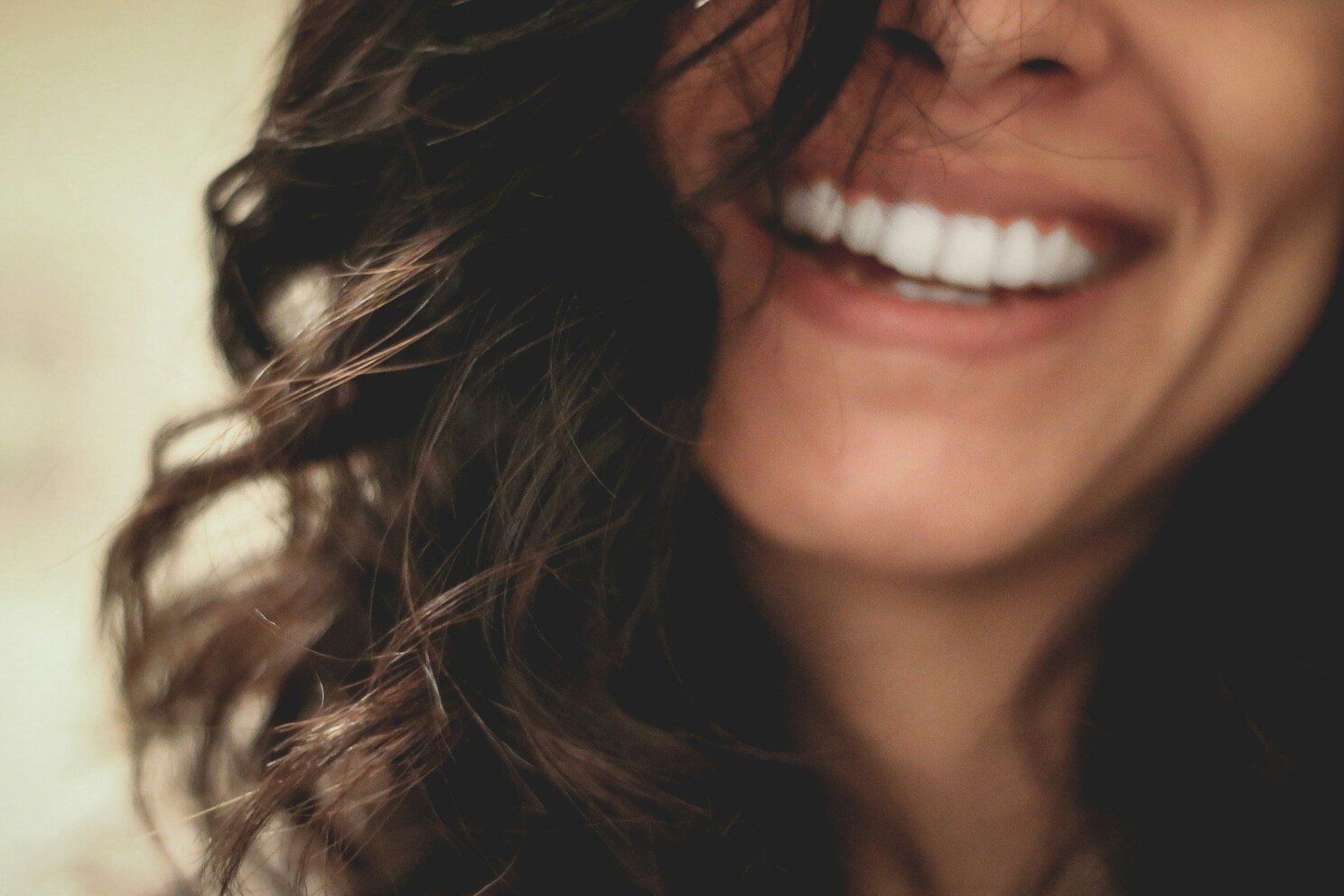 Close-up of a smiling person with wavy dark hair.