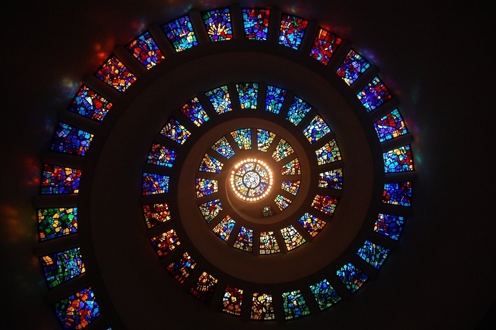 Spiral stained glass structure with vibrant colors viewed from below.